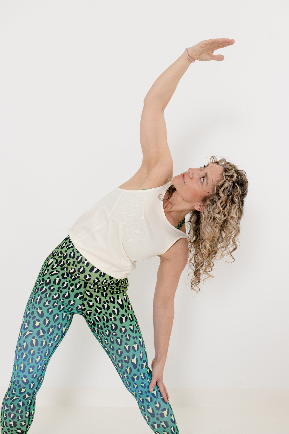 Yoga Jumpsuit mit hellem Oberteil und Leopardenmuster Hose in grün an Blondine mit Locken