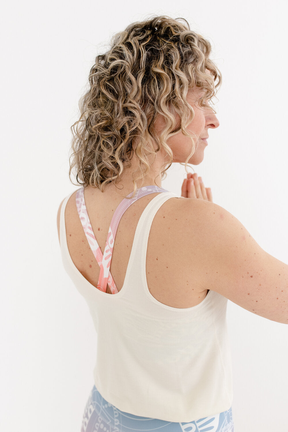 Yoga Jumpsuit mit hellem Oberteil und Sonnenaufgang-farbendem Unterteil in an Blondine mit Locken Von hinten fotografiert