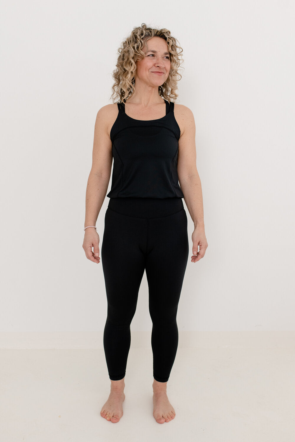 Frau mit blonden Locken und schwarzem YogaJumpsuit