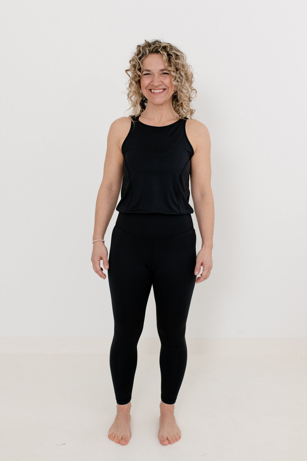 Frau mit Locken und schwarzem YogaJumpsuit 